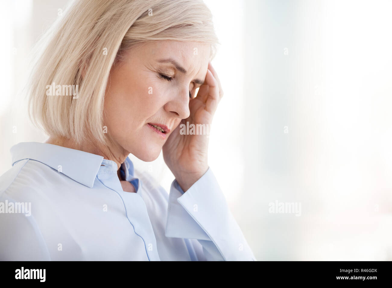 Tired upset mature old businesswoman suffering from strong chron Stock Photo