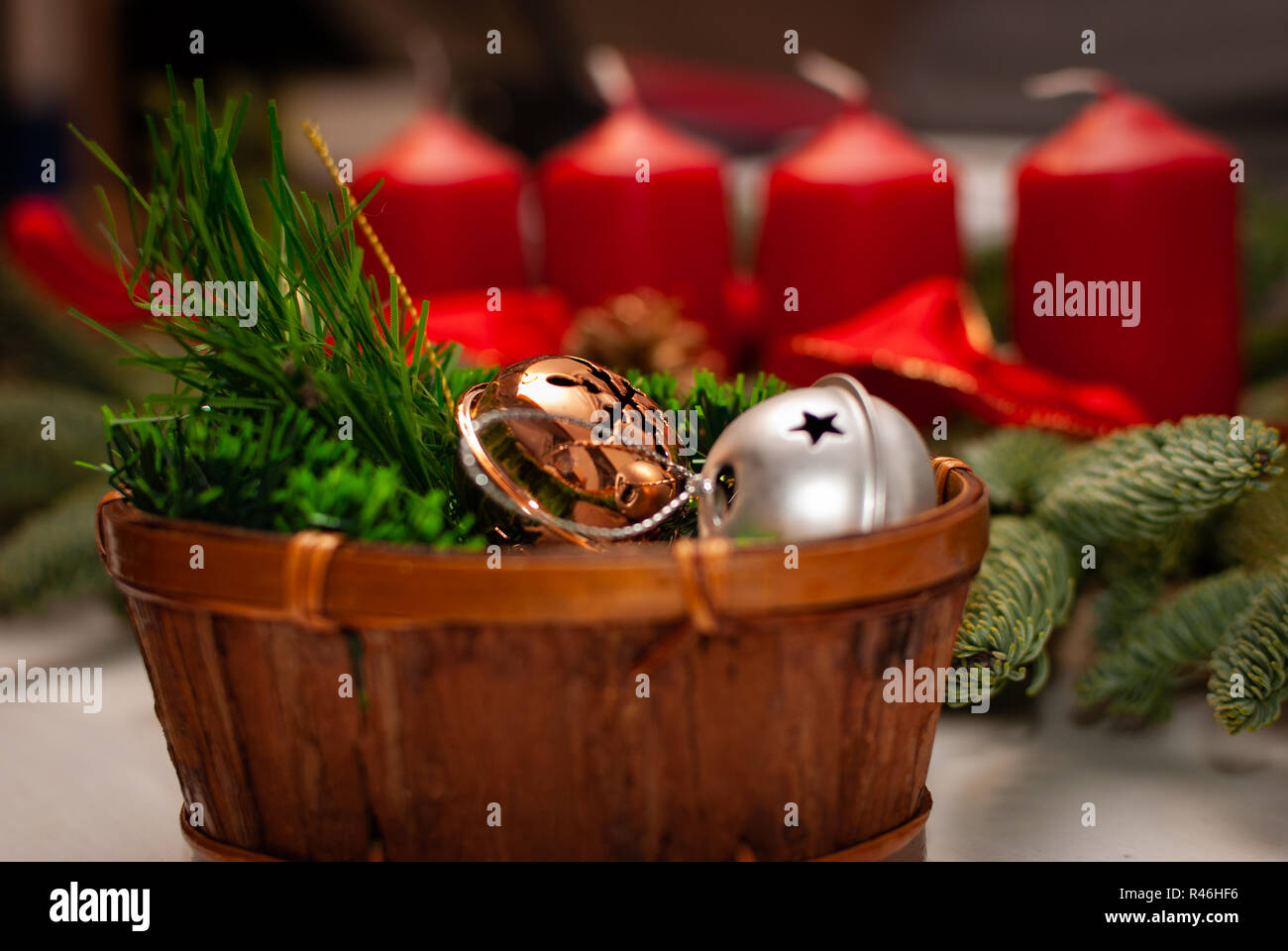 A small wooden box with branches and Christmas bells in front of a advent wreath Stock Photo