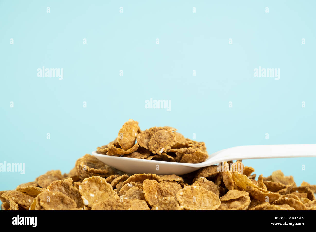 Heap of whole grain cereals in blue background. Healthy breakfast concept: close-up image of spoon full of muesli Stock Photo