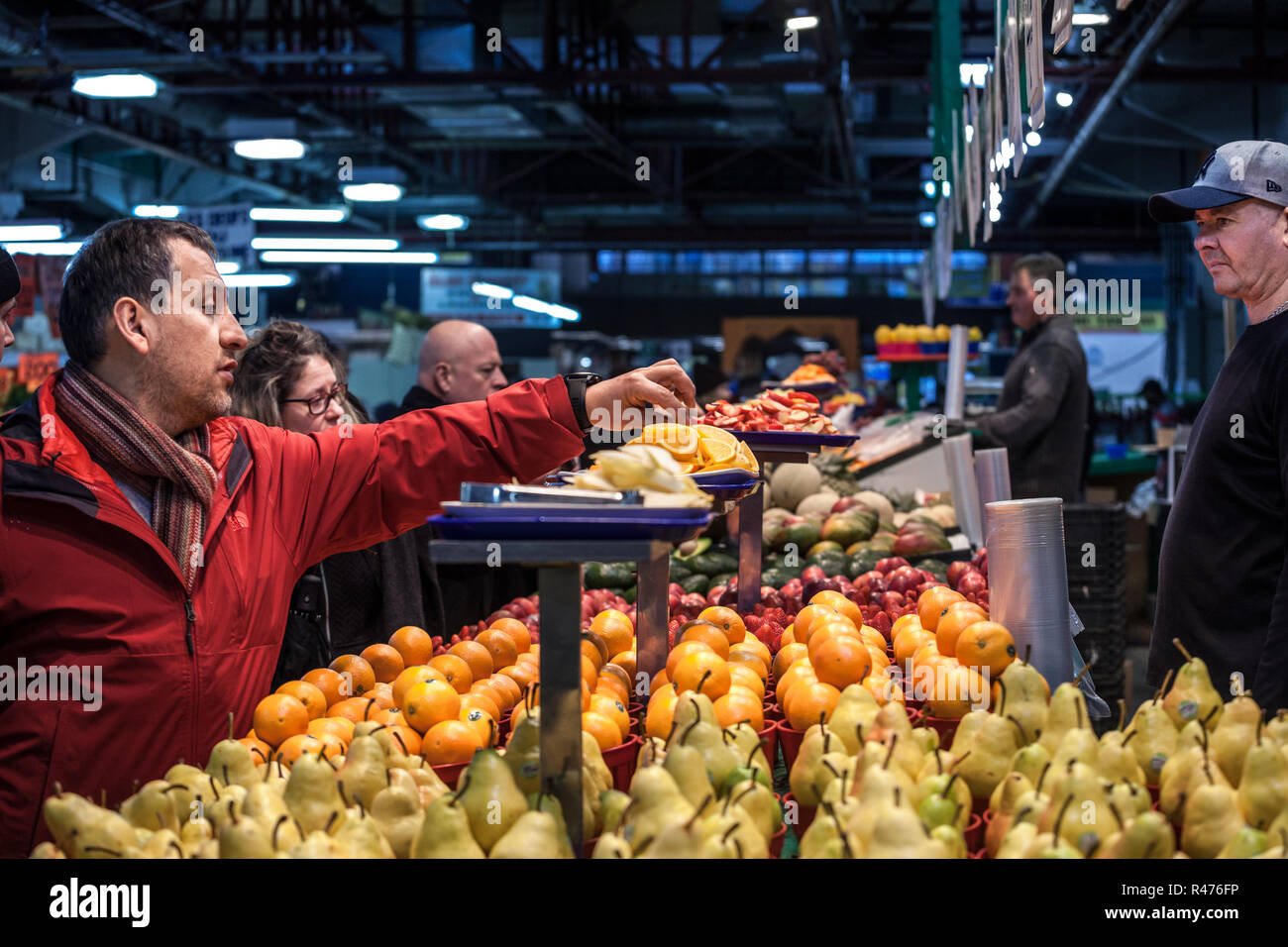 MONTREAL, CANADA - NOVEMBER 3, 2018: Canadian man tasting samples of oranges in Jean Talon Market, in Montreal, Quebec. It is a major landmark & a sym Stock Photo