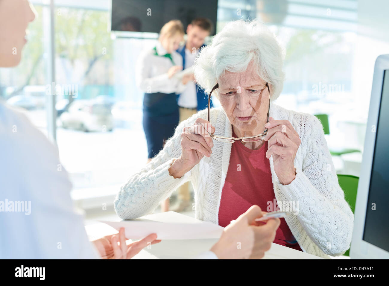 Confused senior lady examining document in bank office Stock Photo - Alamy