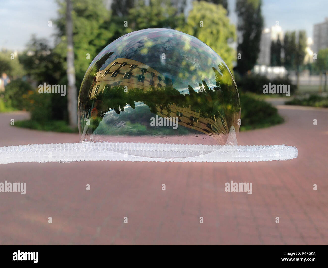 Big soap bubble on a bubble blower. Building and trees reflecting in a huge  bubble in a city park Stock Photo - Alamy