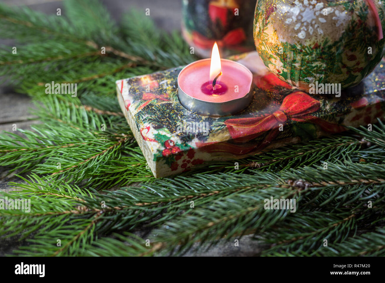 Candle holder decorated with decoupage technique with Christmas motifs and fir branches on a wooden background. Concept of traditional Christmas celeb Stock Photo