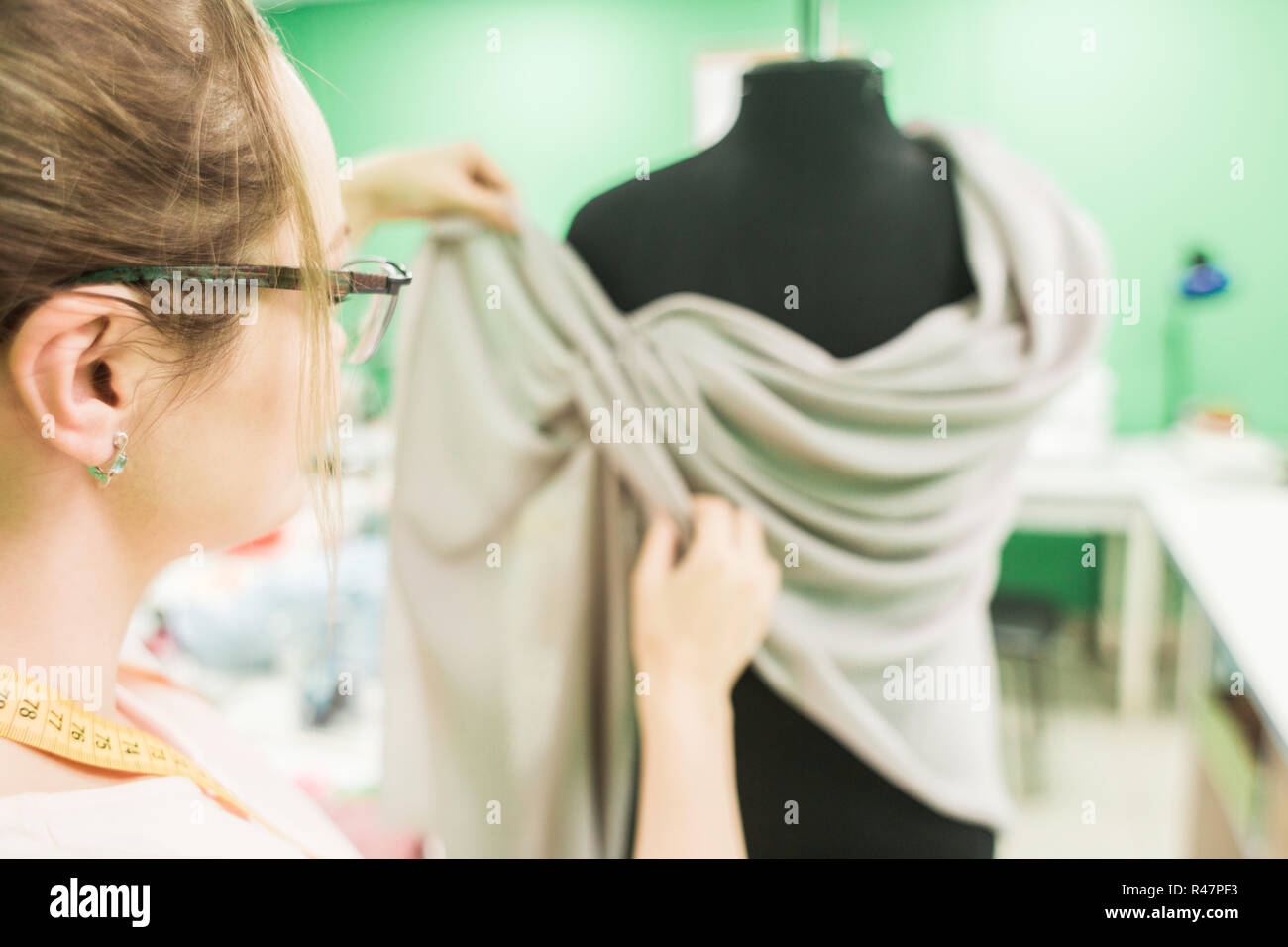 Sewing workshop. Seamstress at work. Young dressmaker working on dress at the studio. Stock Photo