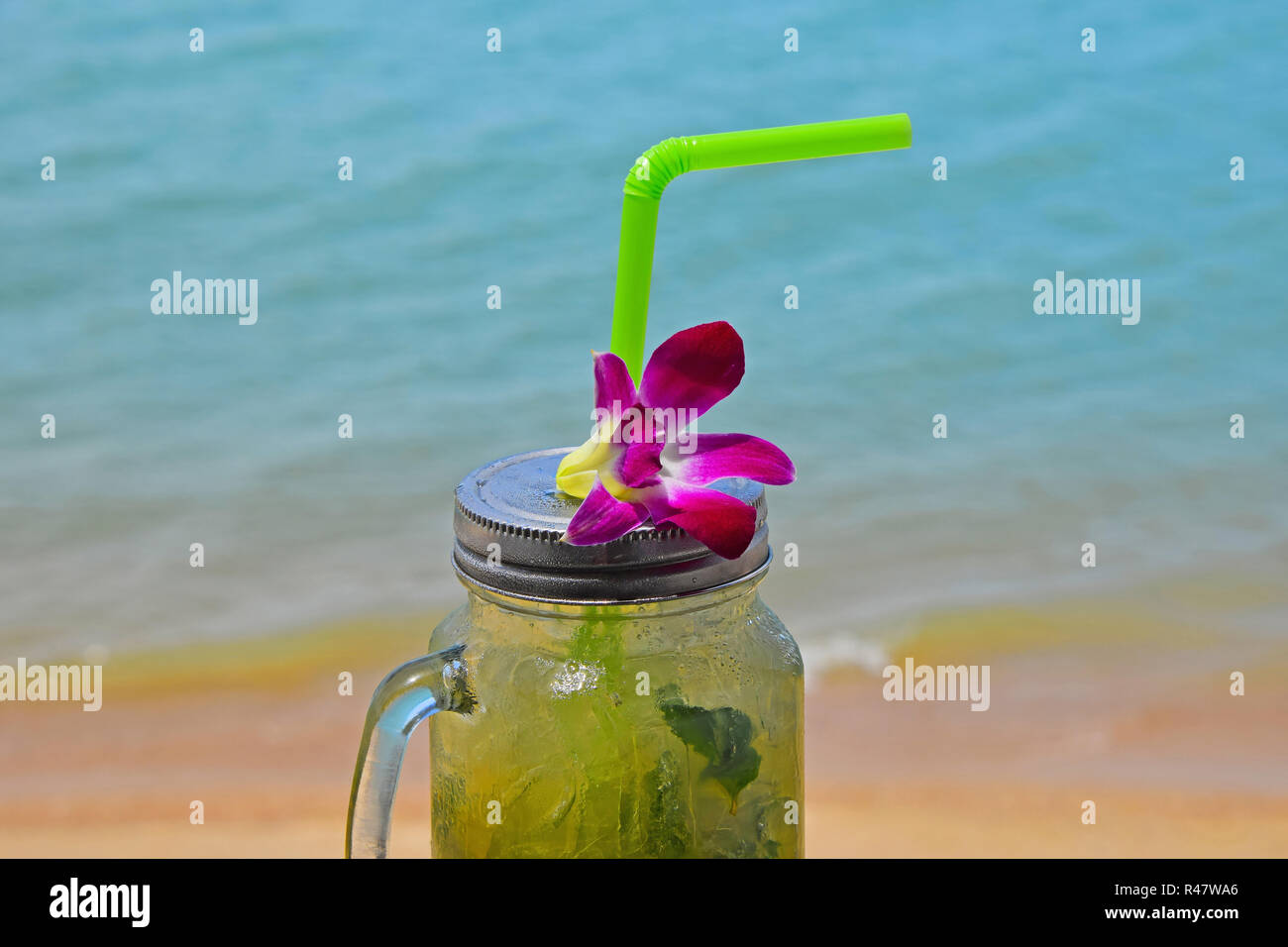 https://c8.alamy.com/comp/R47WA6/big-glass-of-mojito-with-orchid-flower-on-beach-R47WA6.jpg