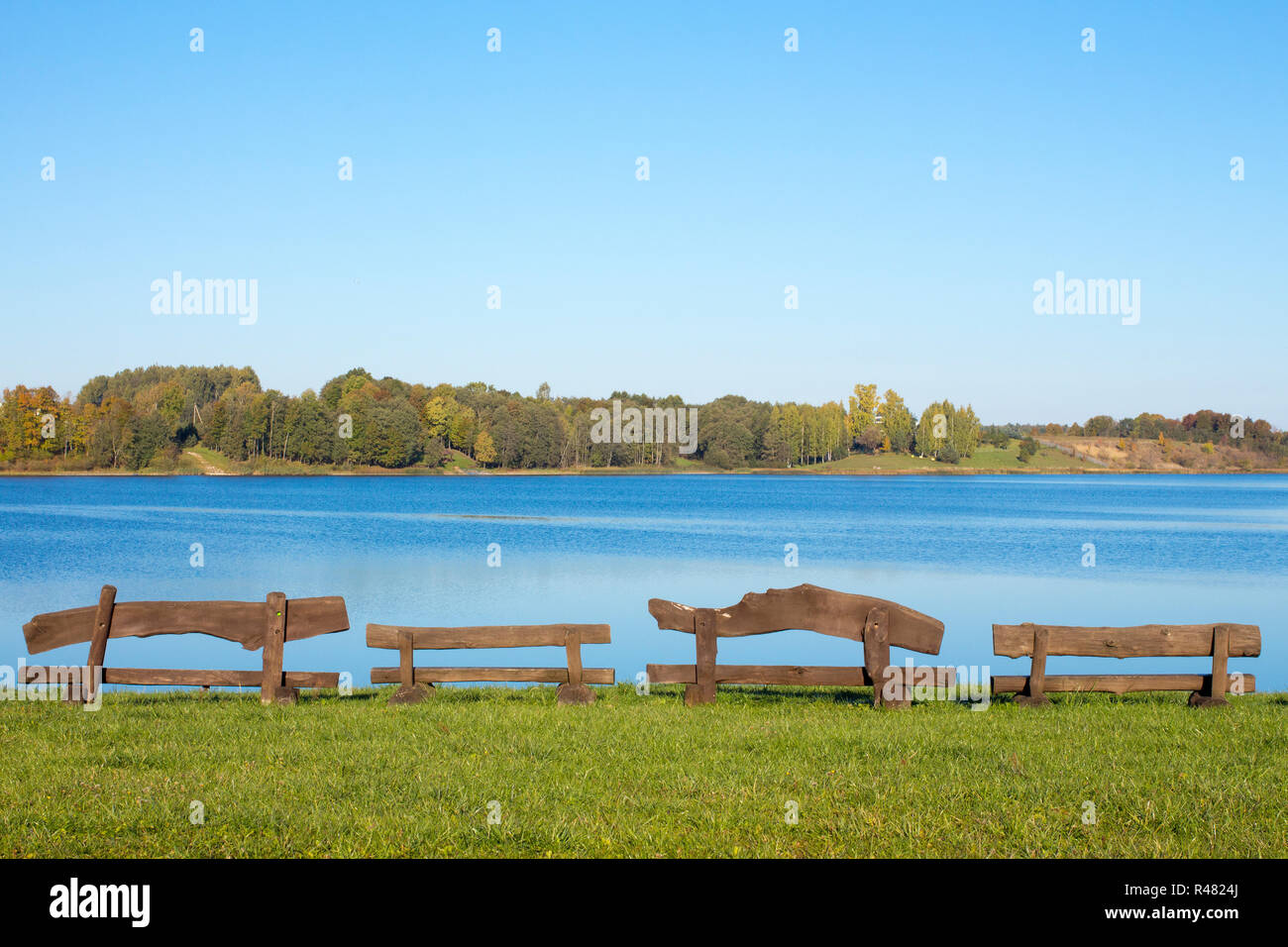 Four wooden benches at the lake Stock Photo