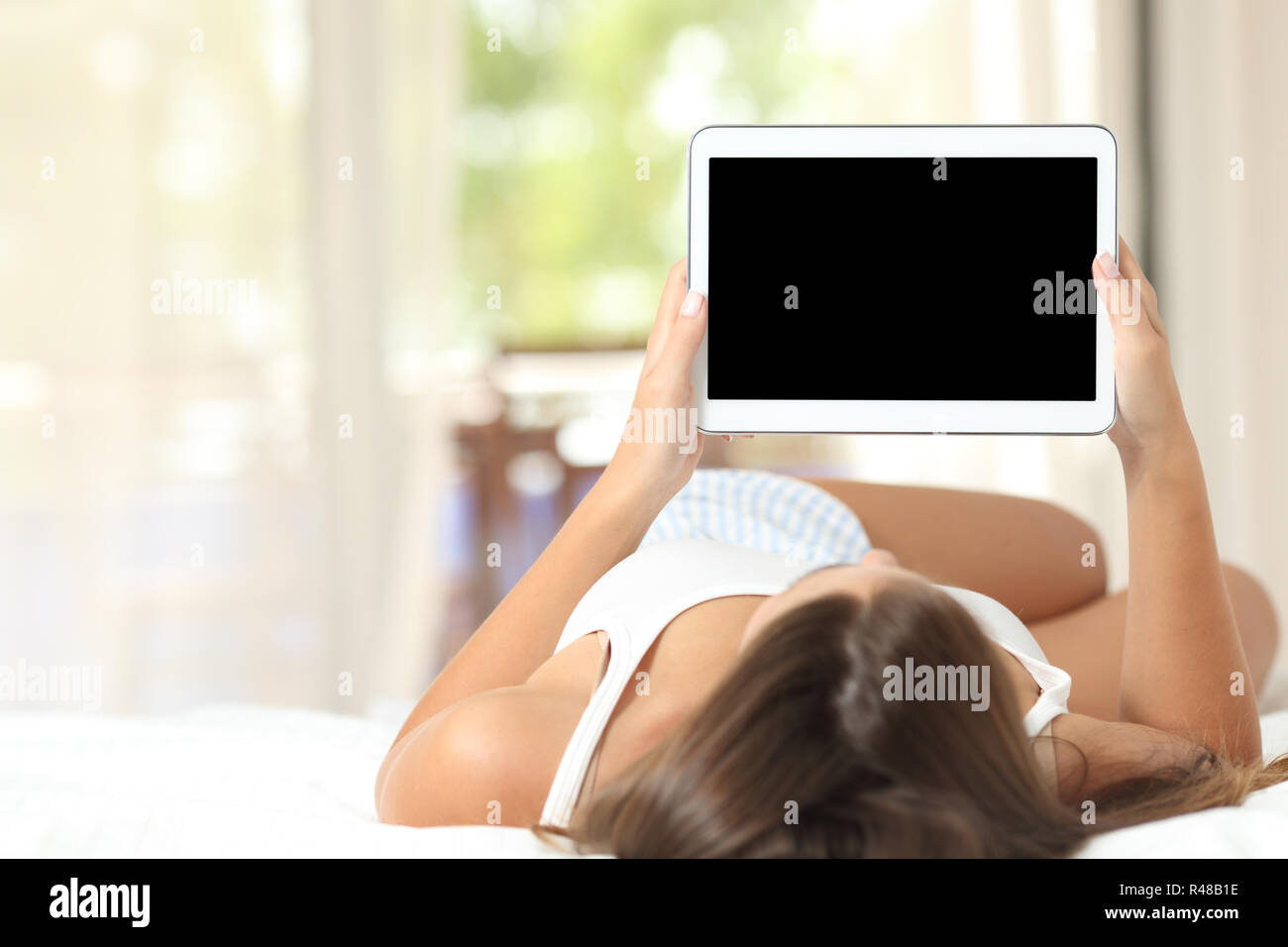 Girl on a bed showing a blank tablet screen Stock Photo