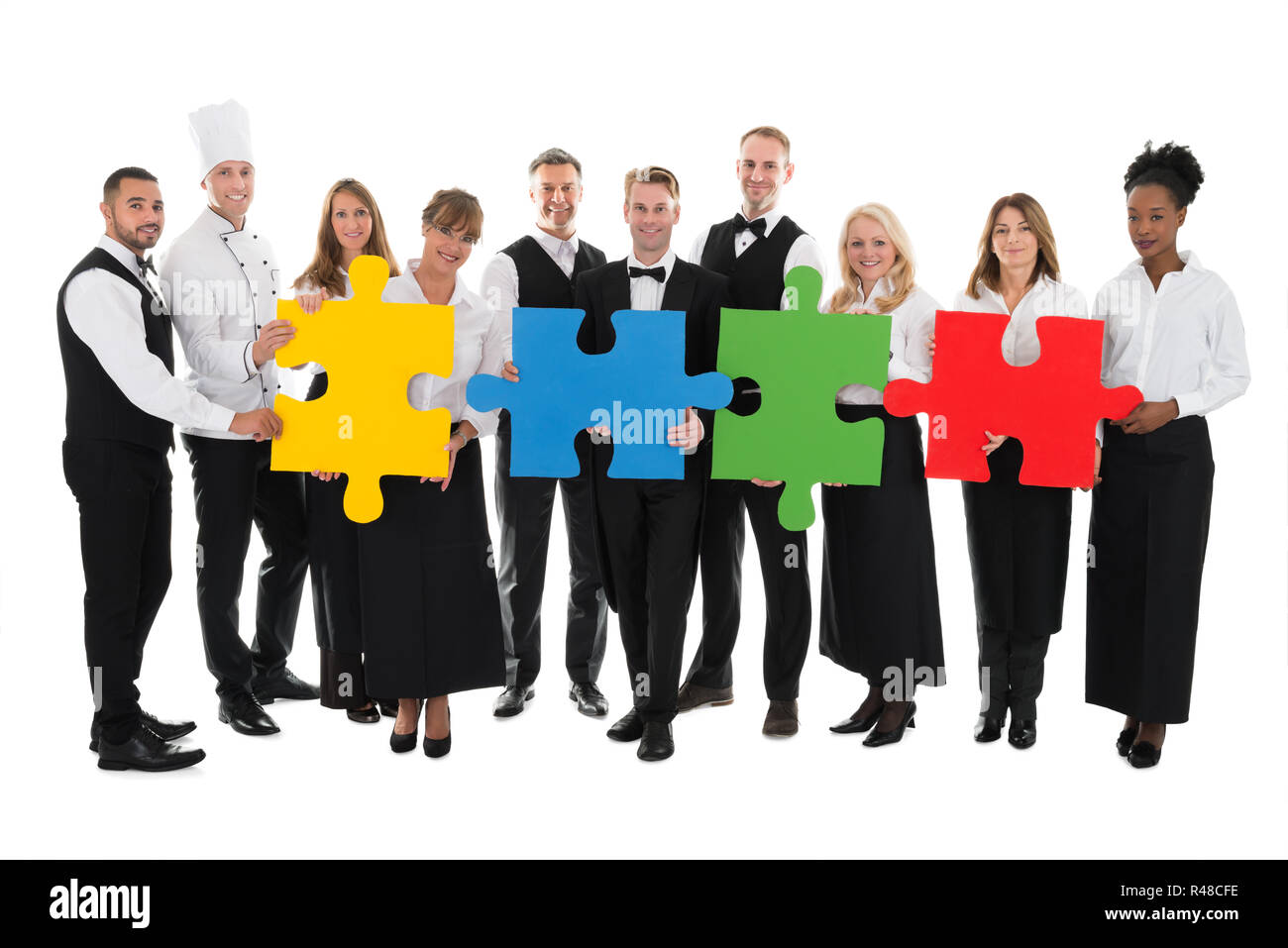 Confident Restaurant Staff Joining Jigsaw Pieces Stock Photo