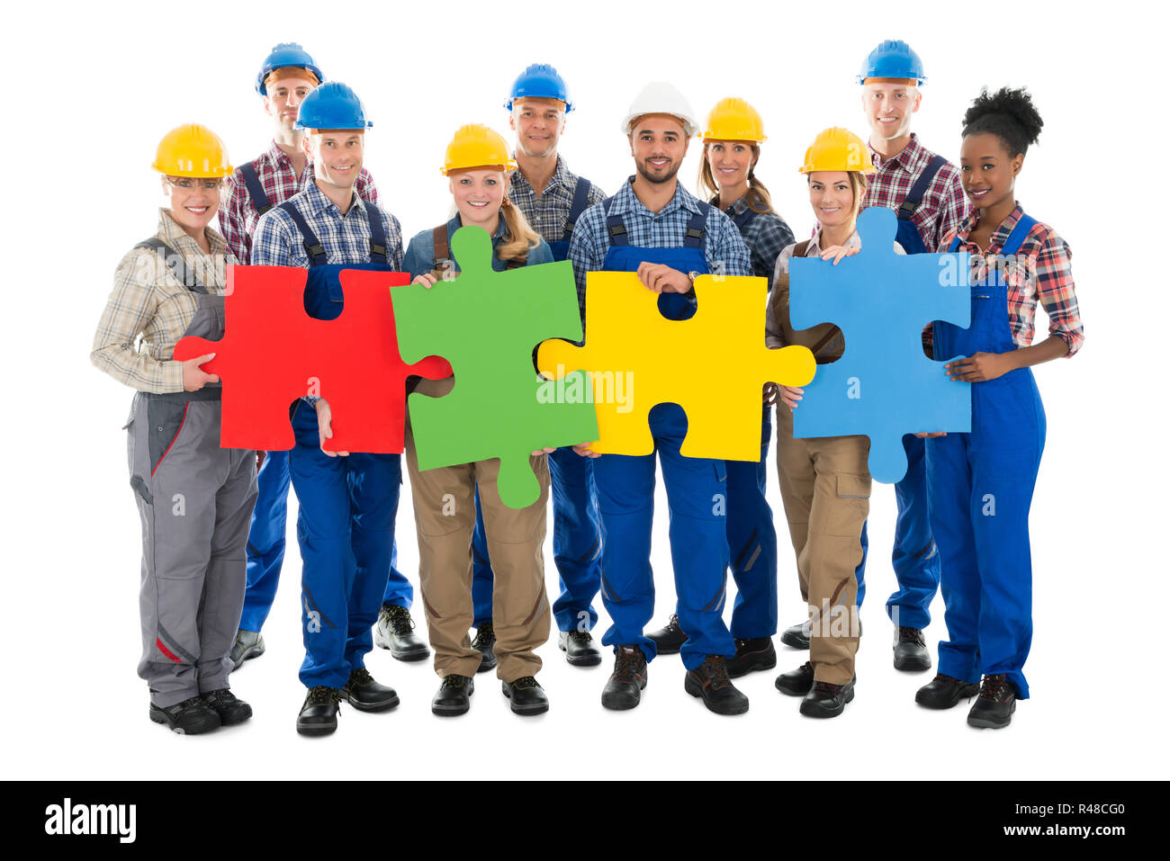 Confident Construction Workers Joining Jigsaw Pieces Stock Photo