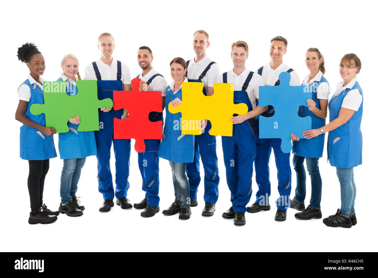 Confident Janitors Holding Jigsaw Pieces In Row Stock Photo