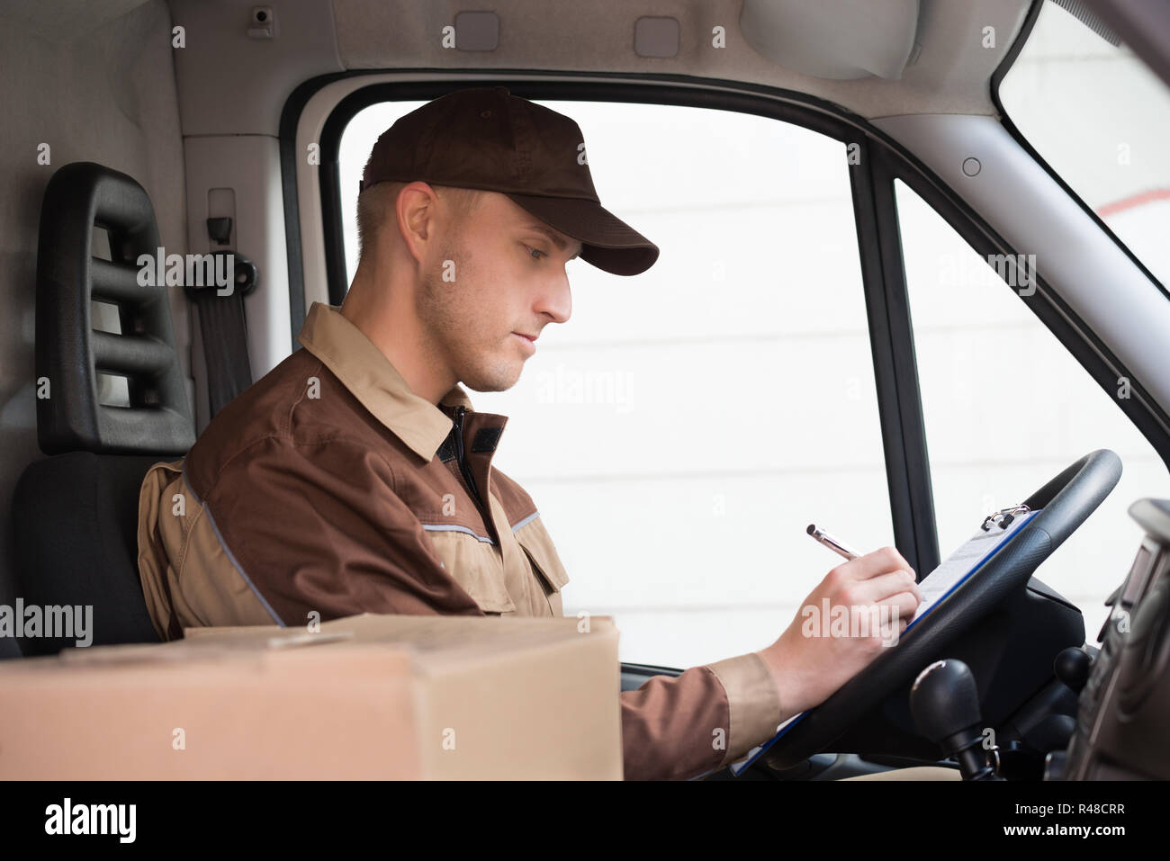 Delivery man in cap writing hi-res stock photography and images - Alamy