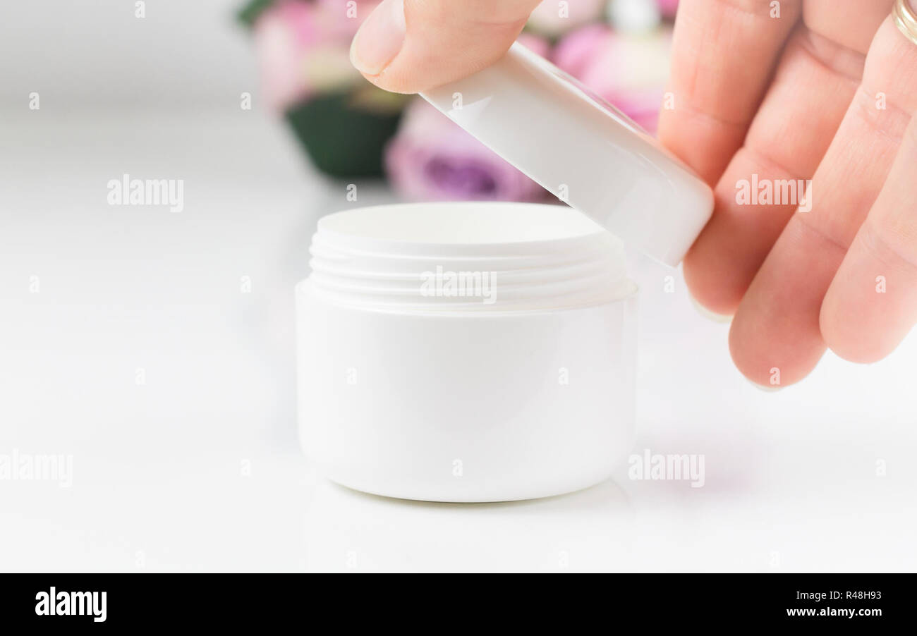 the right hand of a woman opens a jar of cream Stock Photo