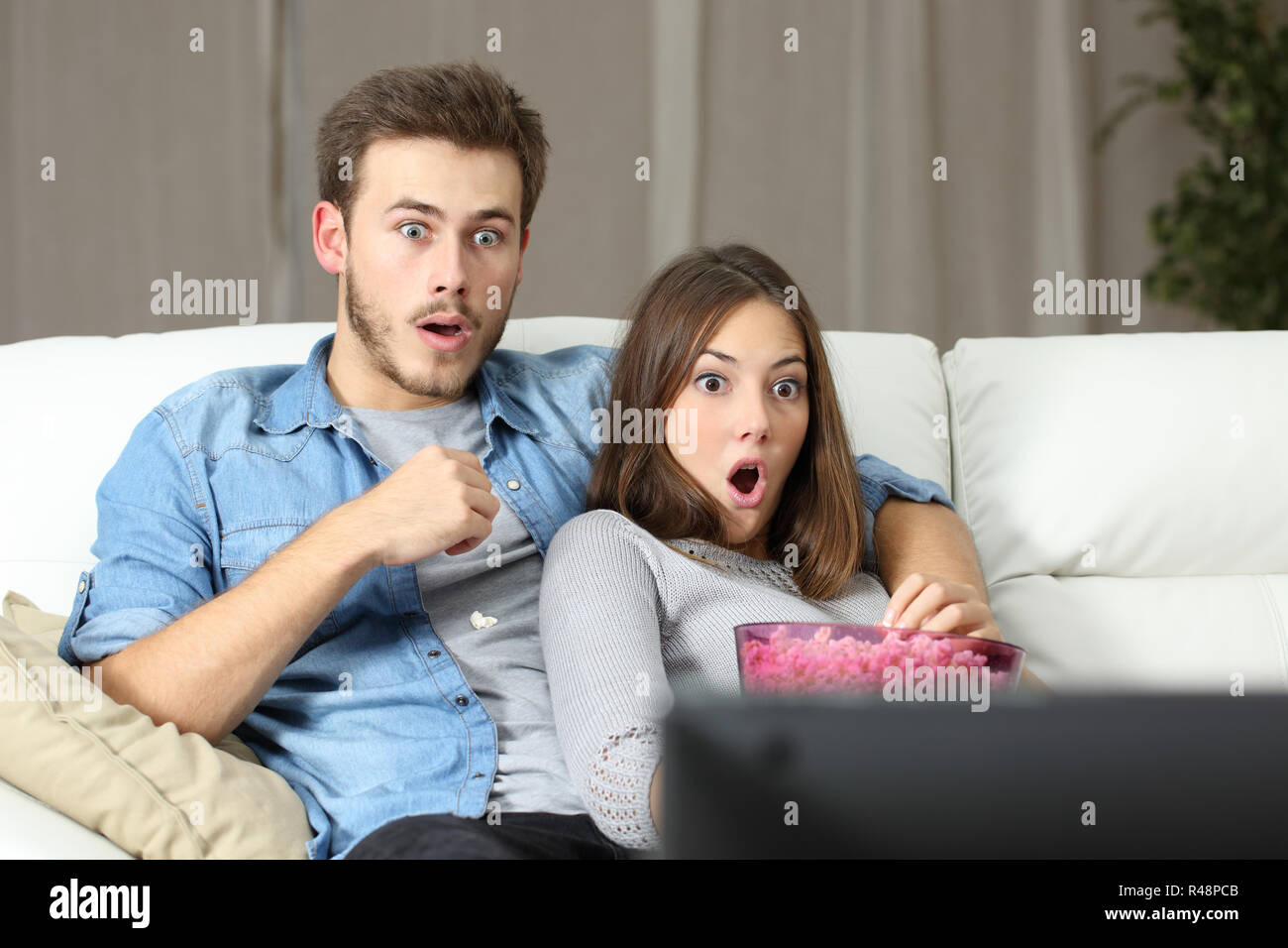 Amazed couple watching tv at home Stock Photo