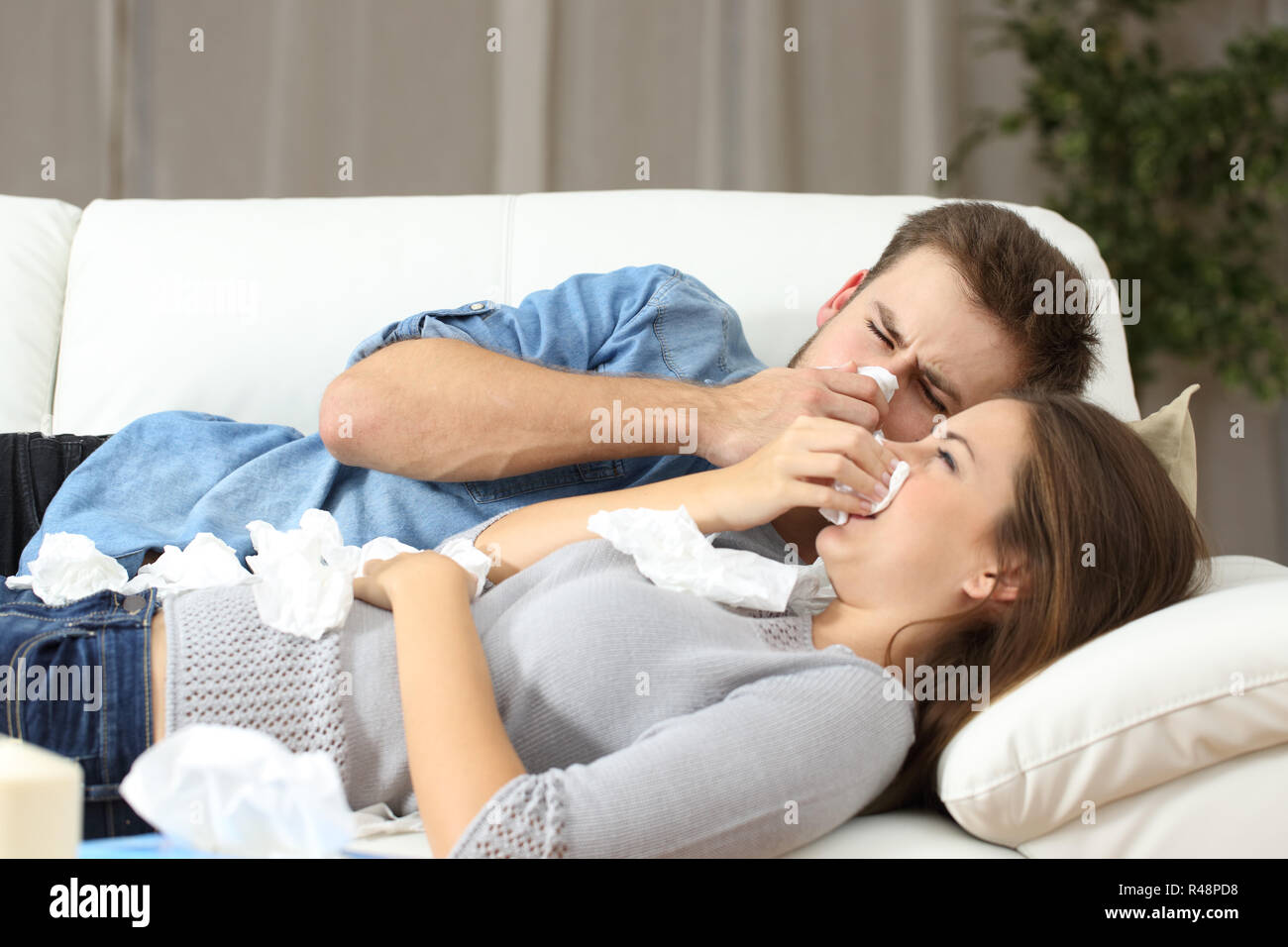 Ill couple sneezing in tissue flu concept Stock Photo