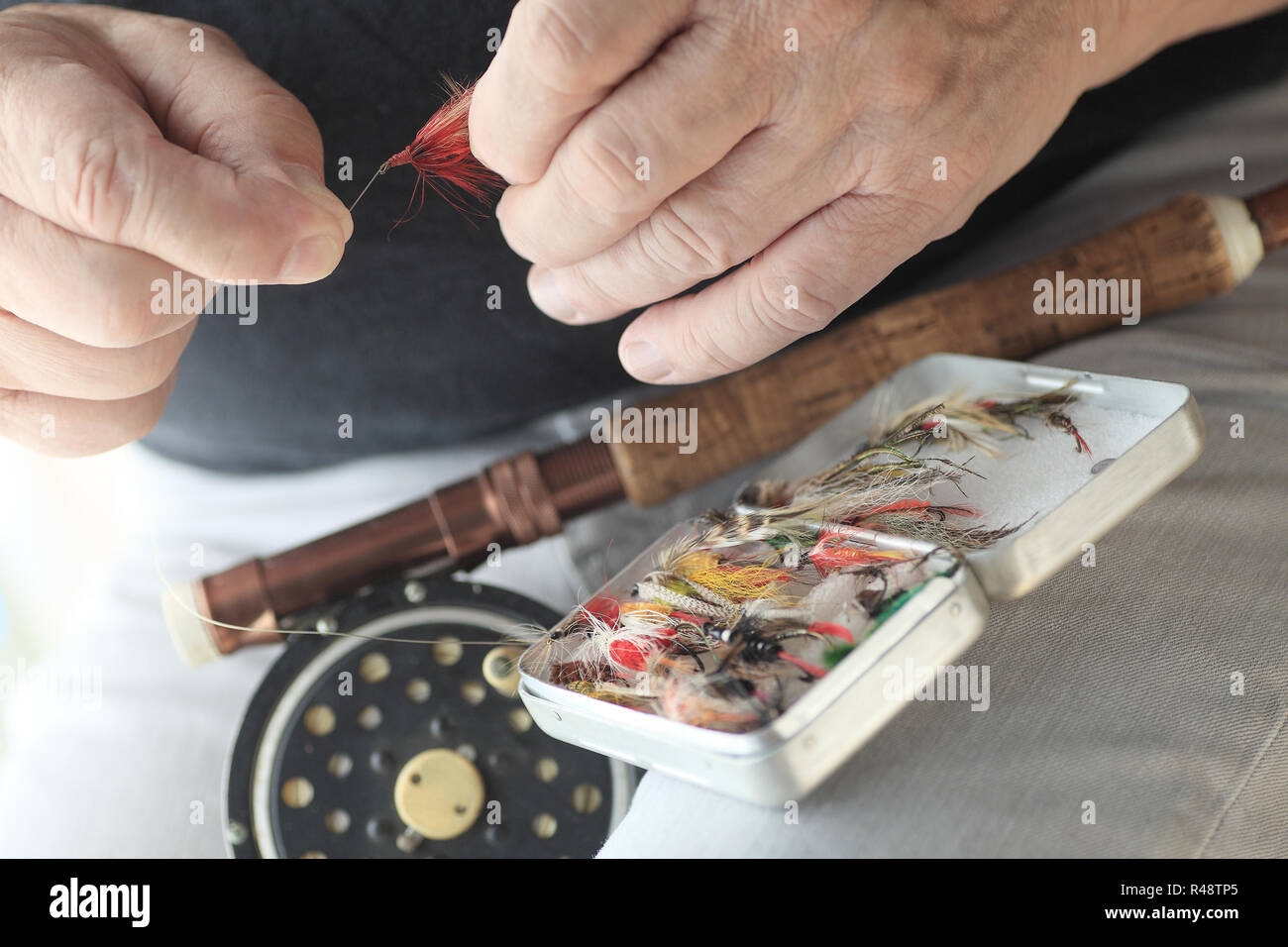 Fly fisherman with gear holds an artificial fly Stock Photo Alamy