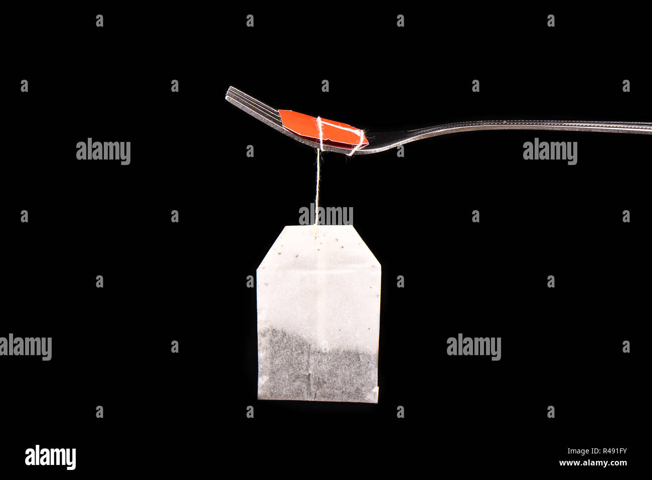 Bag of tea hanging on a fork isolated on a black background Stock Photo