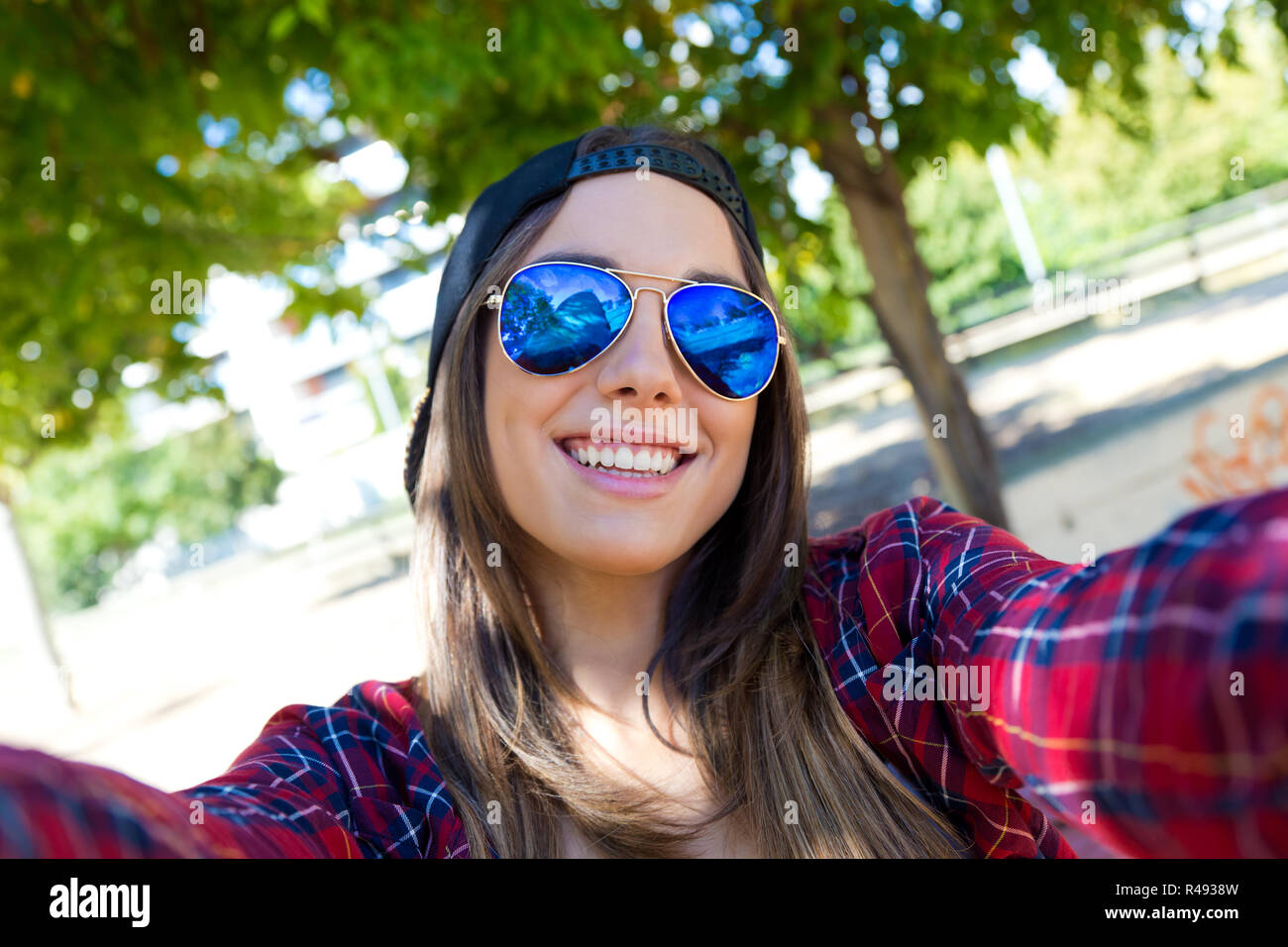 Portrait of beautiful girl taking a selfie with mobile phone in city ...