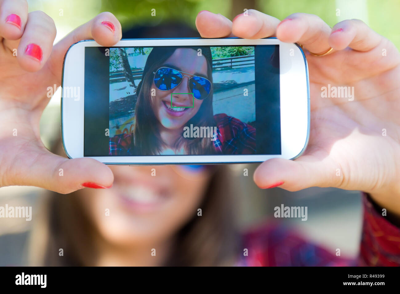 Portrait of beautiful girl taking a selfie with mobile phone in city ...