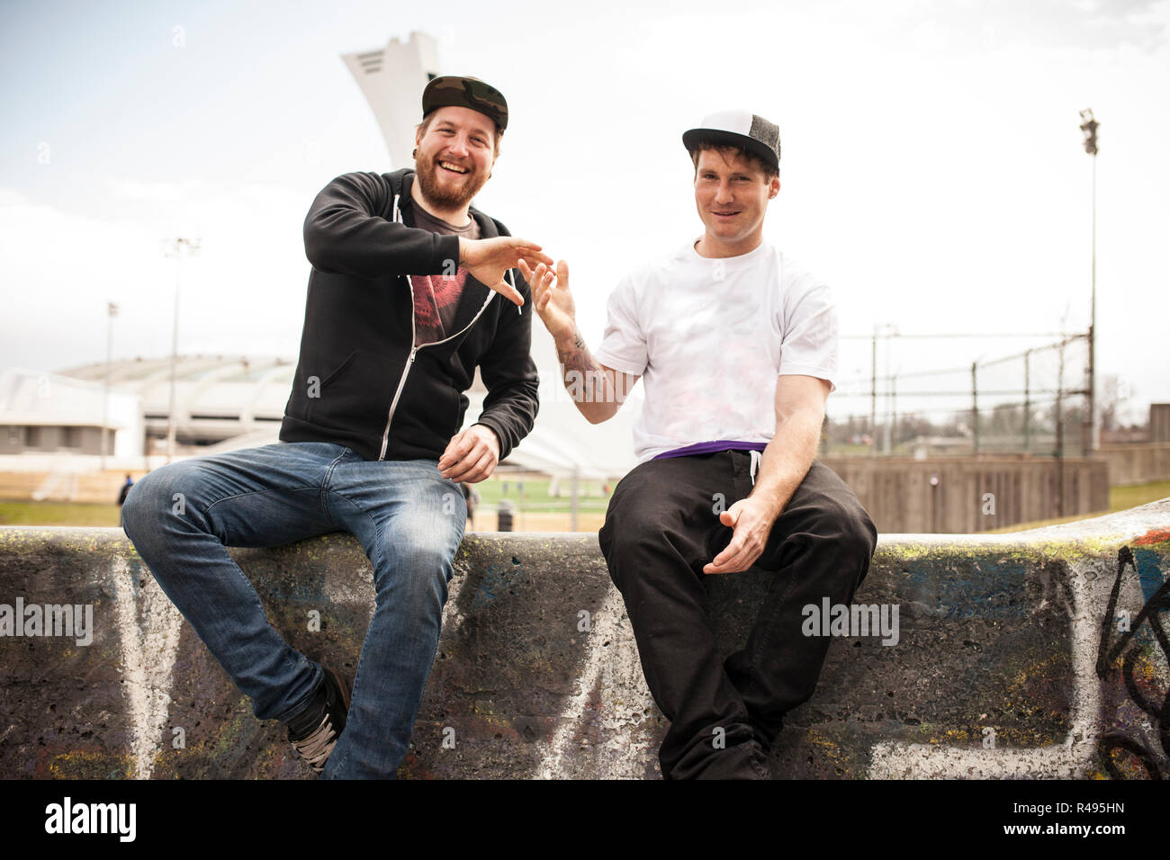 Two buddies bmxing and giving eachother a handshake in concrete ramps Stock Photo