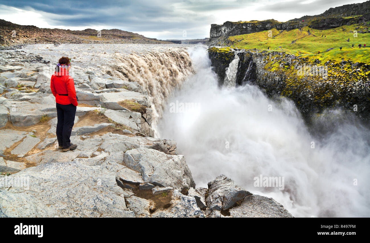 Panoramic view of woman standing near famous Dettifoss waterfall in Vatnajokull National Park, Northeast Iceland Stock Photo