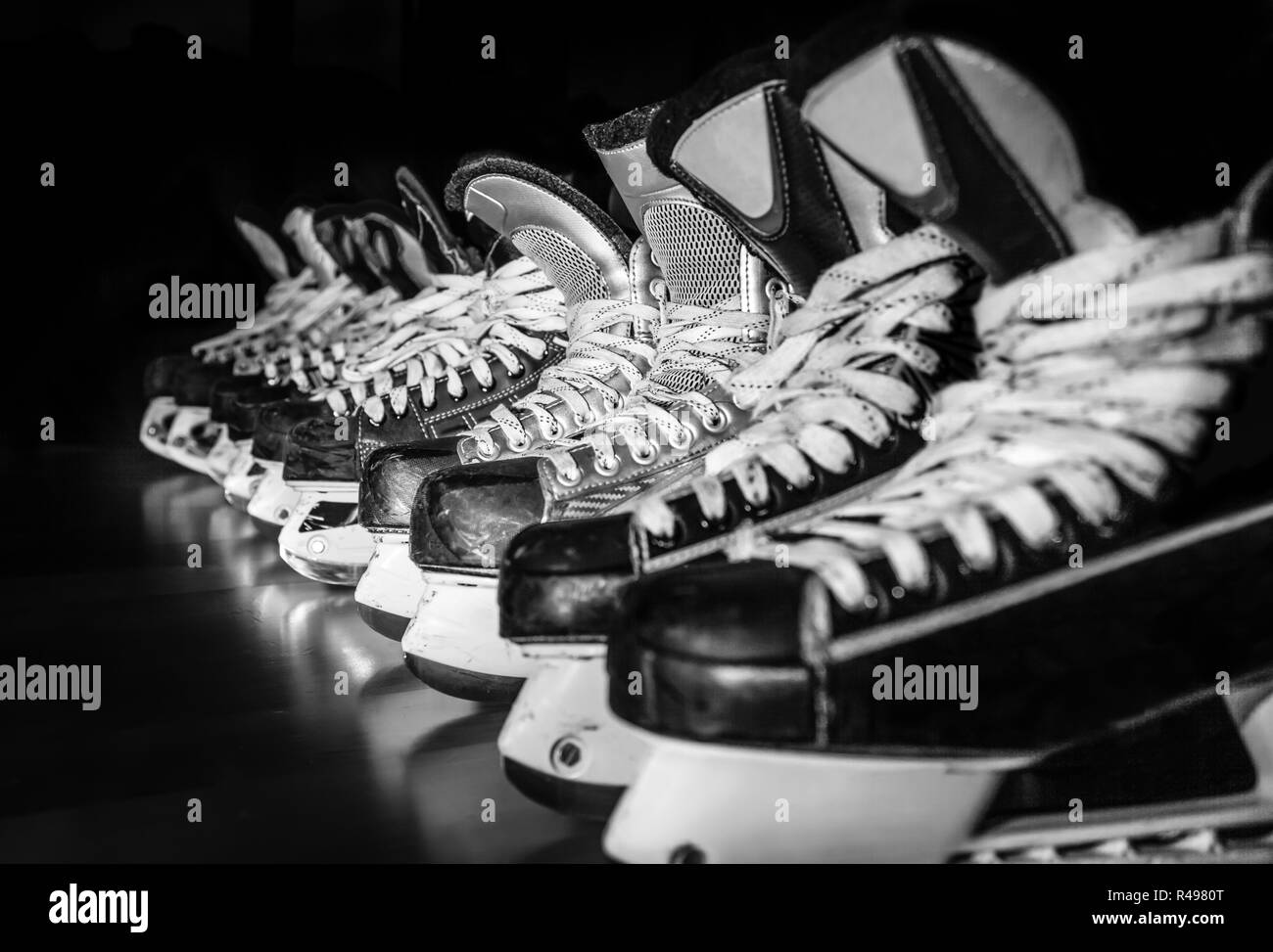 Pairs of ice hockey skates lined up in a dark locker room Stock Photo