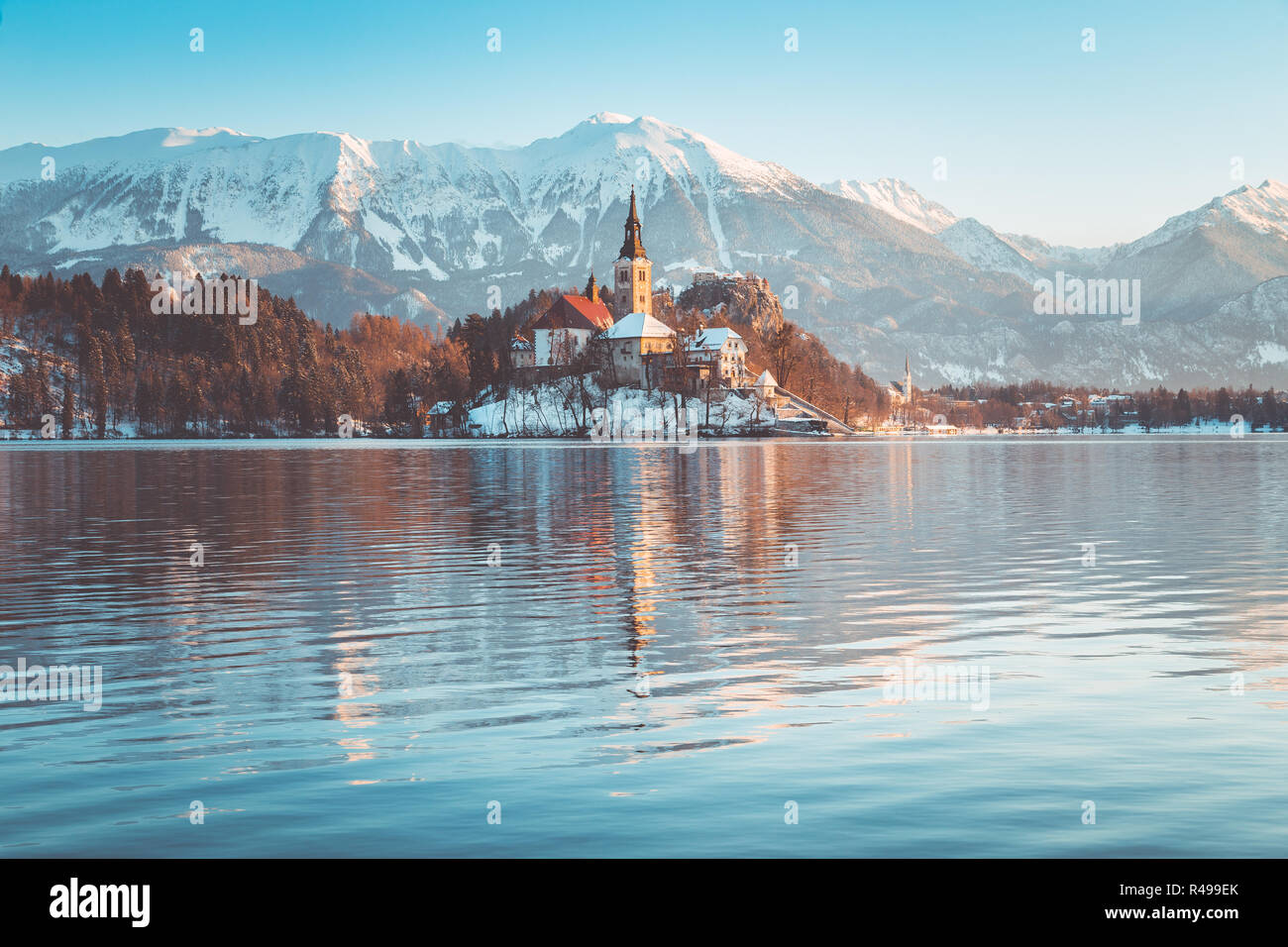 Beautiful view of famous Bled Island (Blejski otok) at scenic Lake Bled with Bled Castle (Blejski grad) and Julian Alps in the background in golden mo Stock Photo