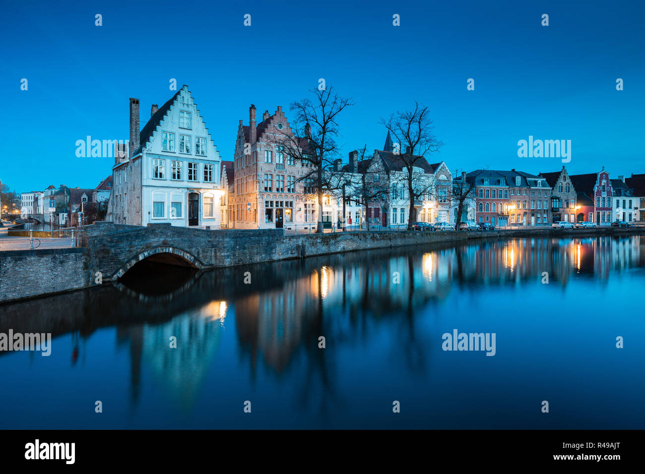 Beautiful twilight view of the historic city center of Brugge with old houses along famous Potterierei canal illuminated during blue hour at dusk, Bru Stock Photo