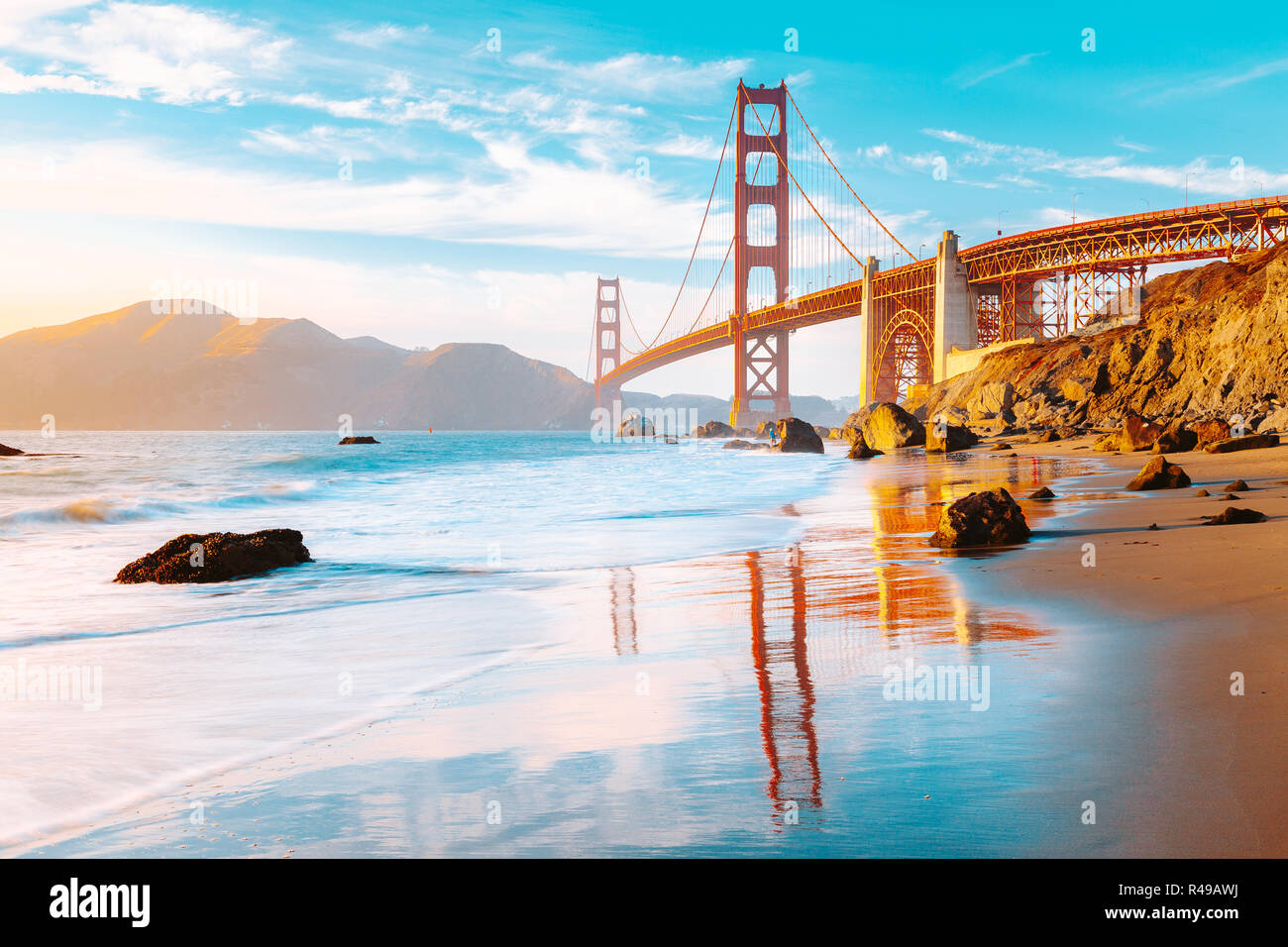 Famous Golden Gate Bridge seen from scenic Baker Beach in beautiful golden evening light on a sunny day with blue sky and clouds, San Francisco, USA Stock Photo