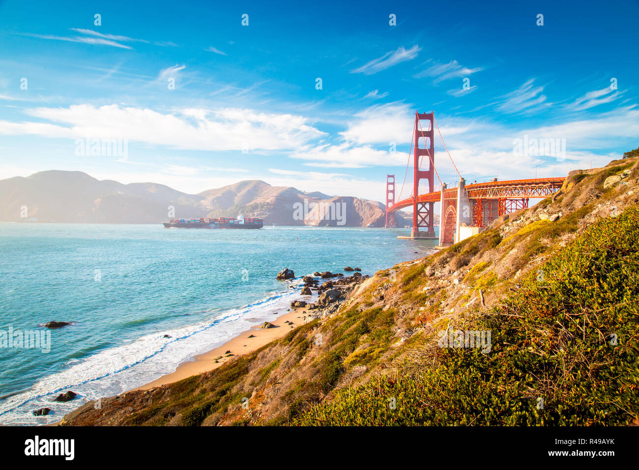 Classic view of famous Golden Gate Bridge with cargo ship on a sunny ...