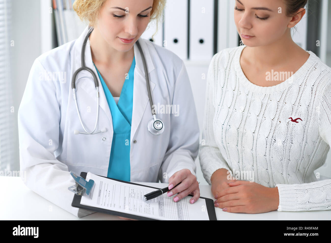 Happy Blonde Female Doctor And Patient Discussing Medical Examination