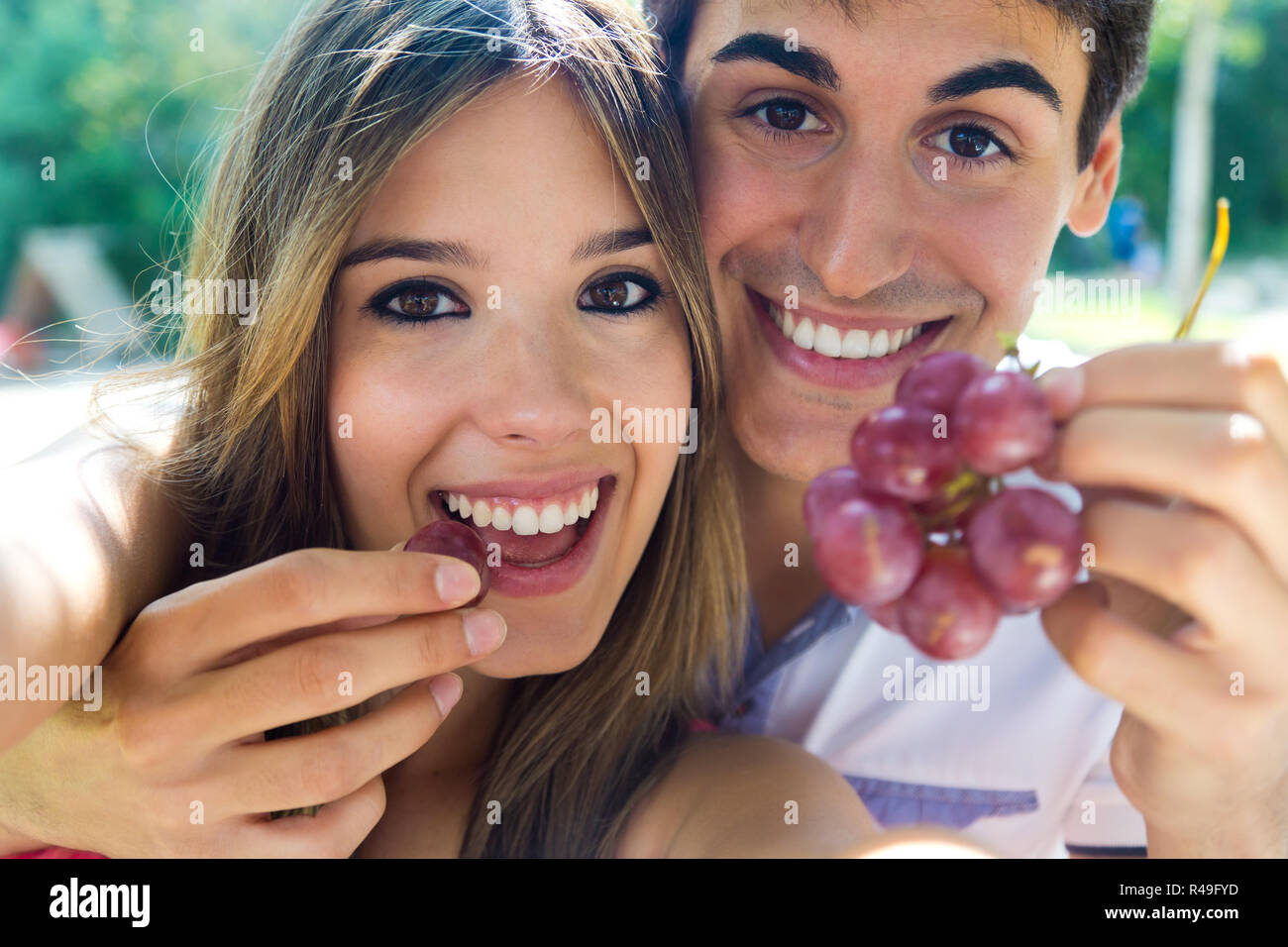 Young couple eating grapes on romantic picnic in countryside. Stock Photo