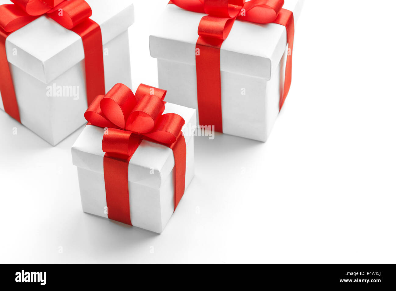 Three gift boxes with red ribbons on white background Stock Photo - Alamy