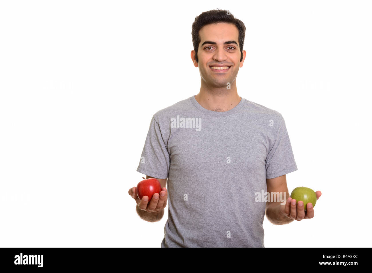 Young happy Persian man holding red and green apple ready for gy Stock ...