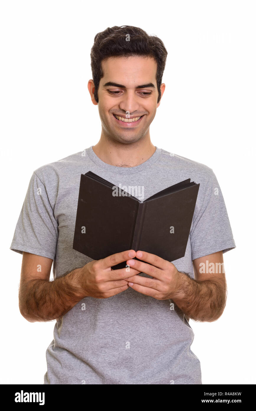 Portrait of young happy Persian man reading book Stock Photo