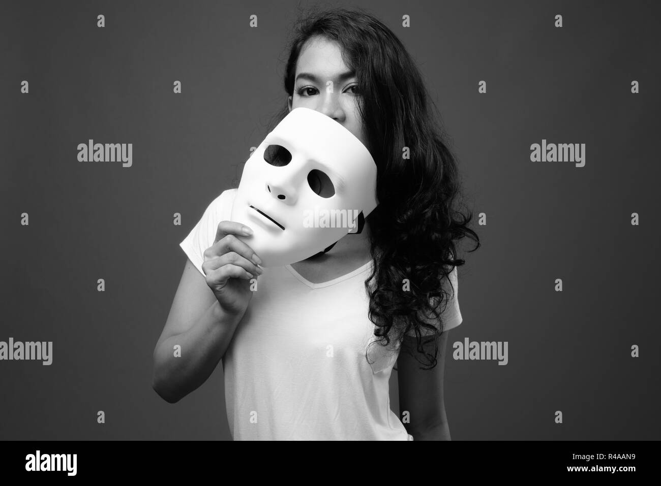 Portrait of young beautiful Asian woman holding mask Stock Photo
