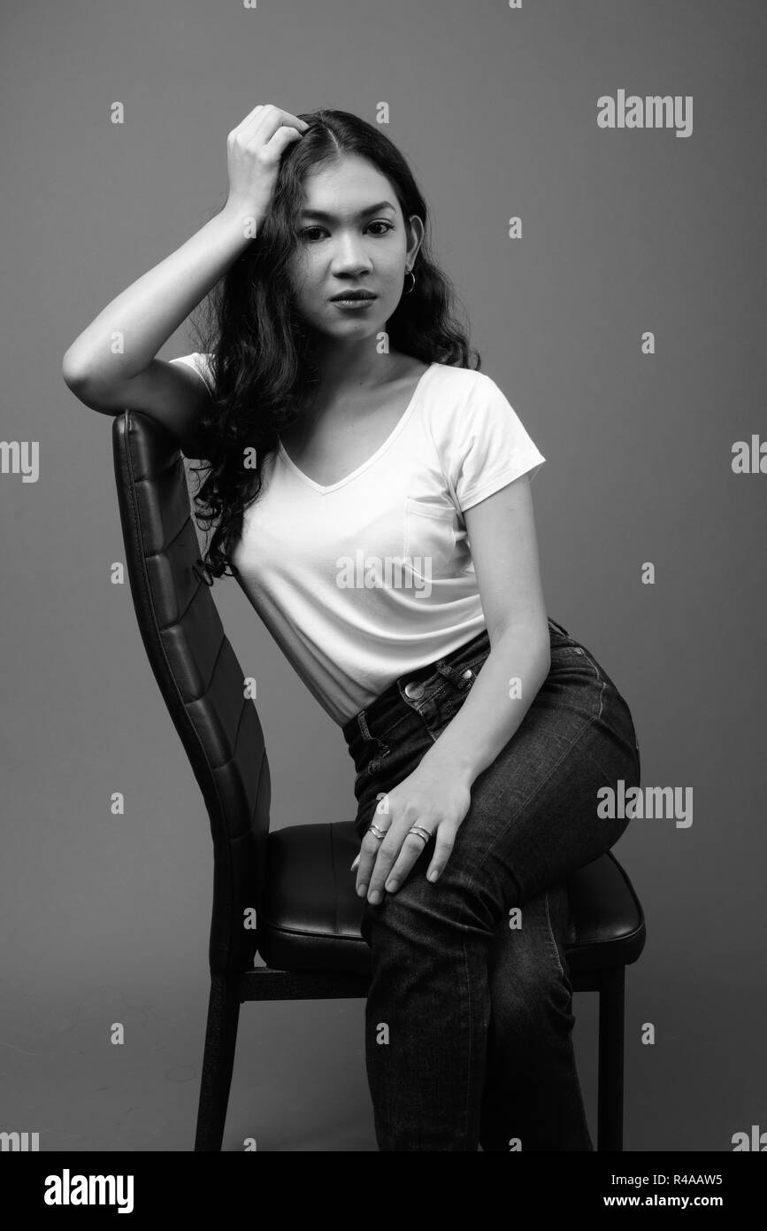 Young beautiful Asian woman sitting studio shot in black and white Stock Photo