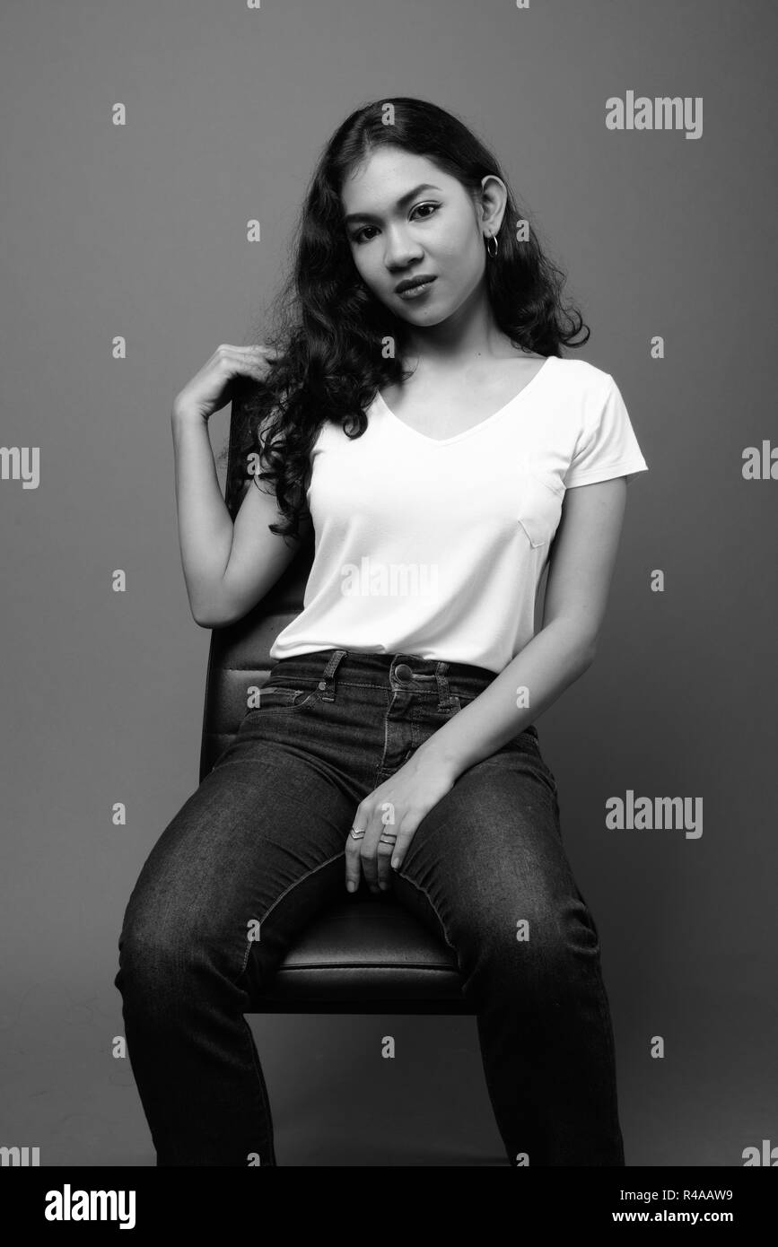 Young beautiful Asian woman sitting studio shot in black and white Stock Photo