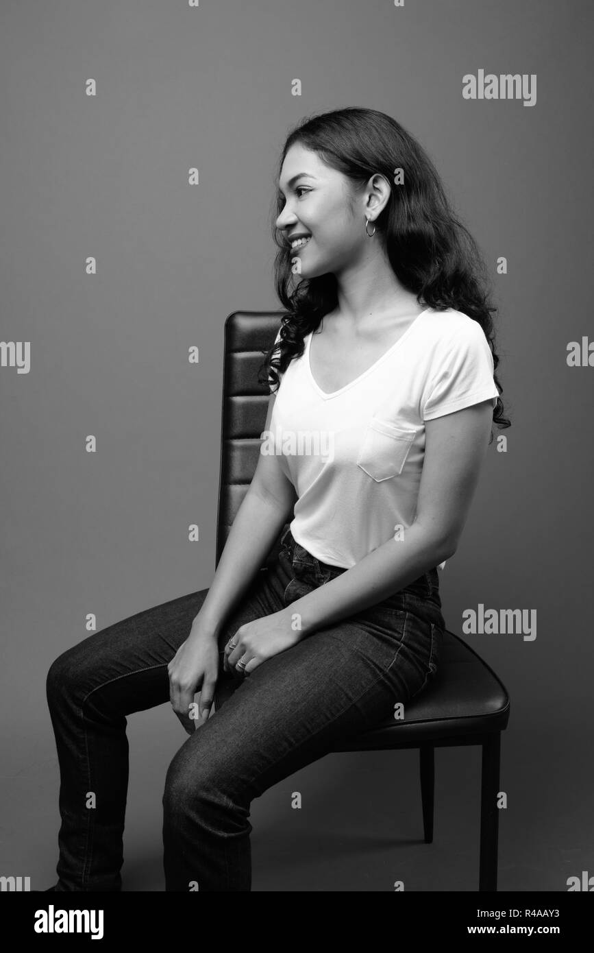 Young beautiful Asian woman sitting studio shot in black and white Stock Photo