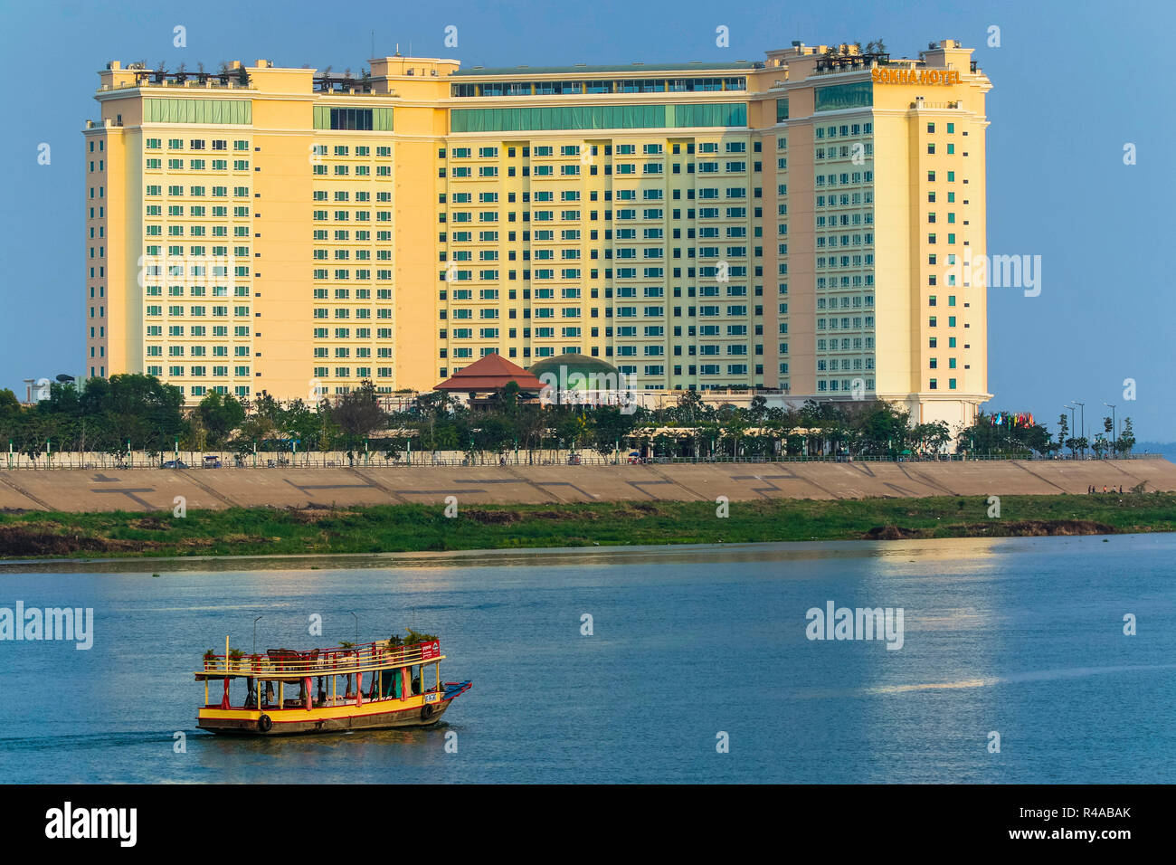 Sunset cruise boat & Sokha hotel at the confluence of the Tonle Sap & Mekong rivers; central riverfront, Phnom Penh, Cambodia Stock Photo