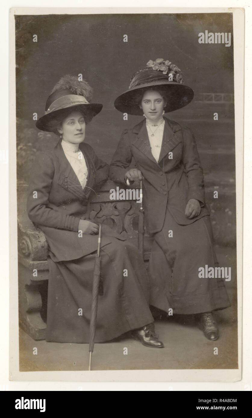 Original Edwardian studio portrait postcard of 2 Edwardian ladies wearing wide-brimmed hats sitting down holding umbrellas, Leeds, U.K. circa 1909, 1910 Stock Photo