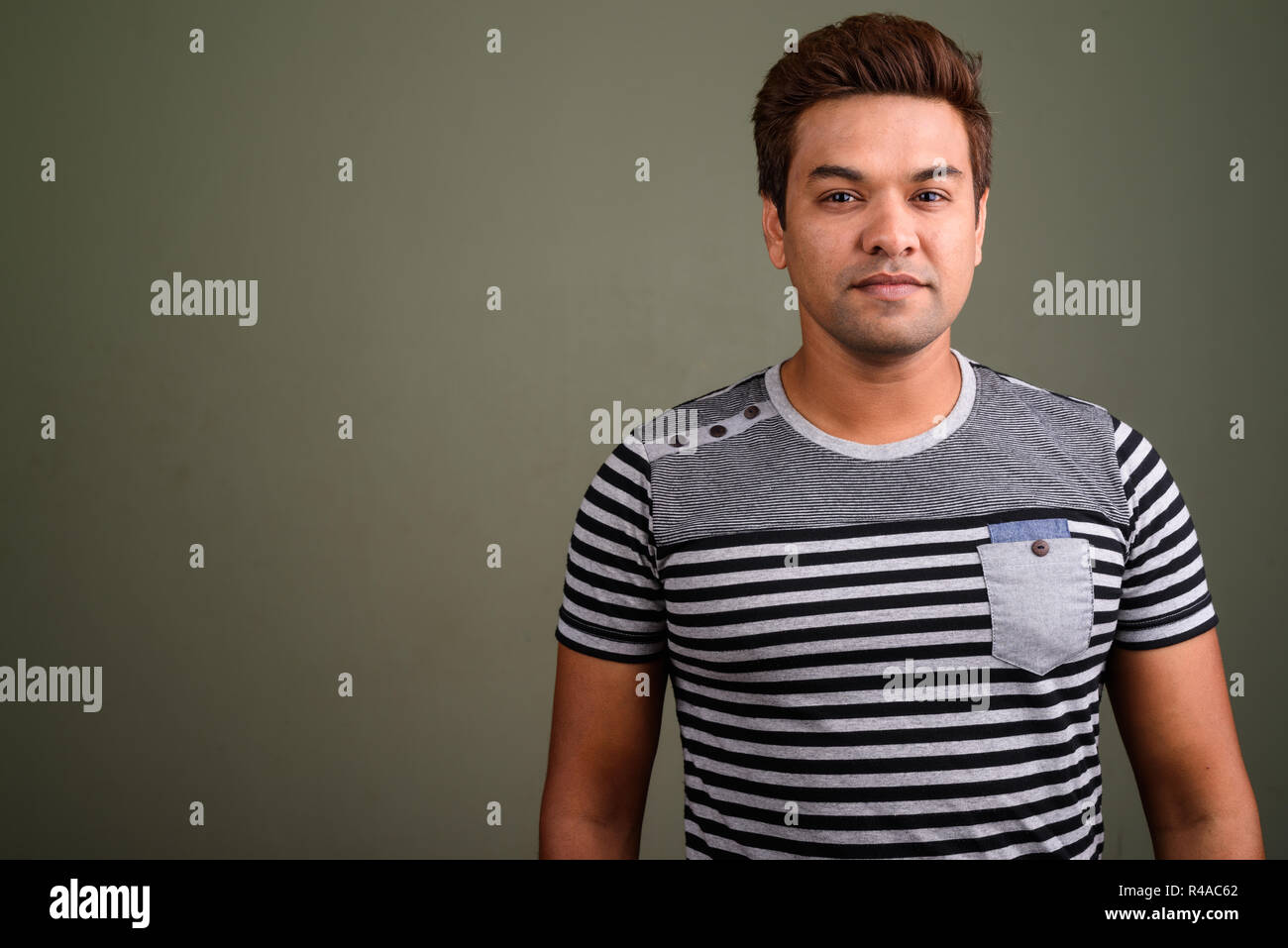 Indian man wearing striped shirt against colored background Stock Photo