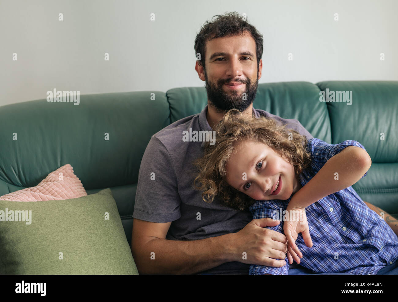 Smiling father and son sitting on their sofa at home Stock Photo - Alamy