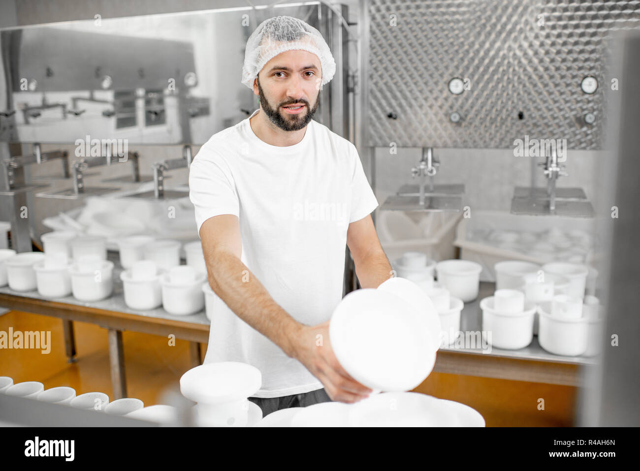Man in uniform forming cheese into the plastic molds putting them under ...