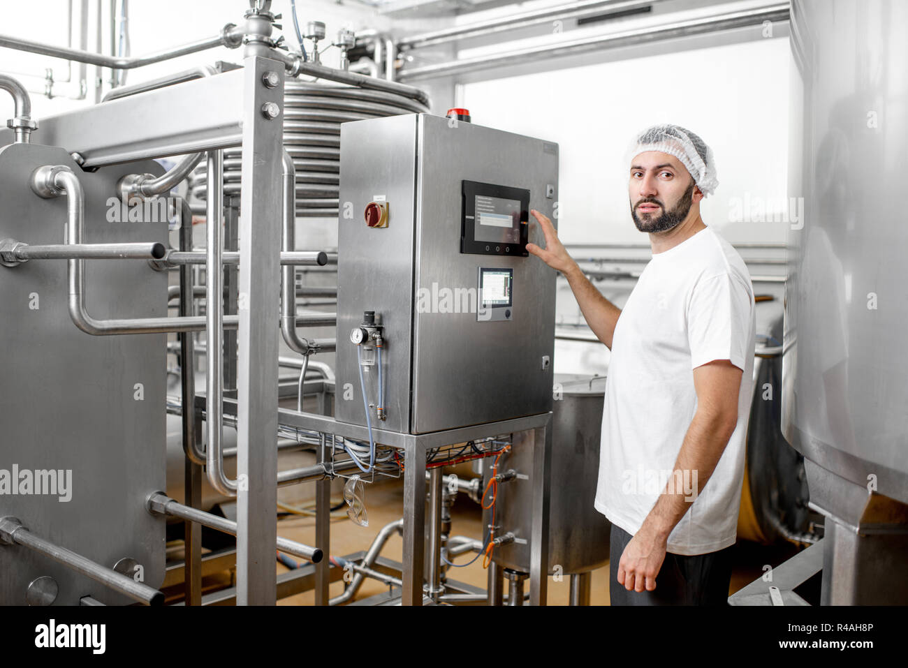 Worker operating pasteurizer using the control panel at the cheese or milk manufacturing Stock Photo