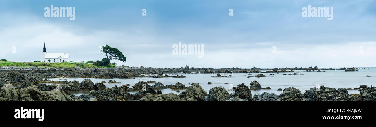 Panorama shot of the Christ Church Raukokore perched on a rocky, rugged beach. New Zealand, Opotiki. Stock Photo