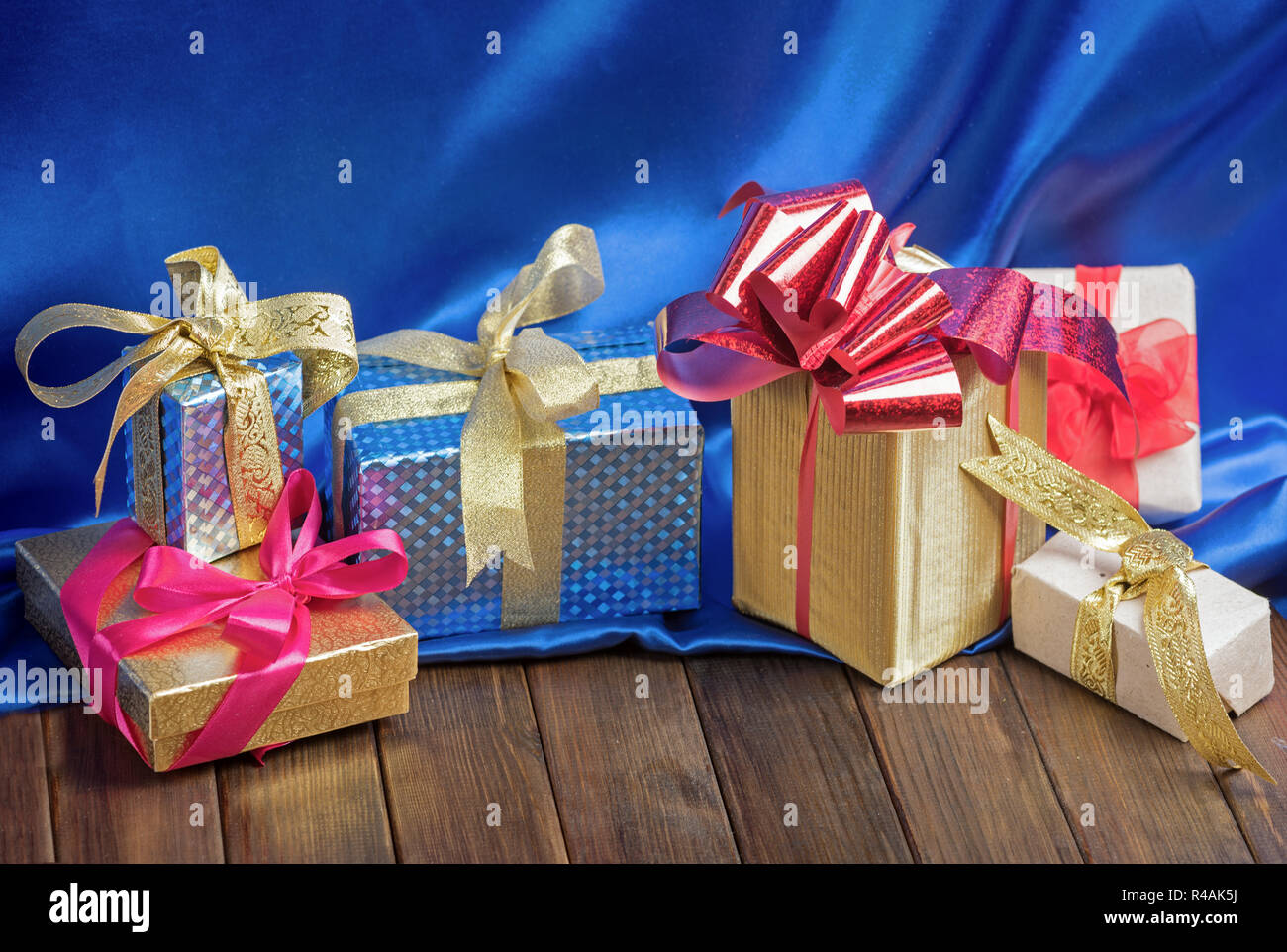 Gift boxes with ribbons on wooden table and blue silk Stock Photo