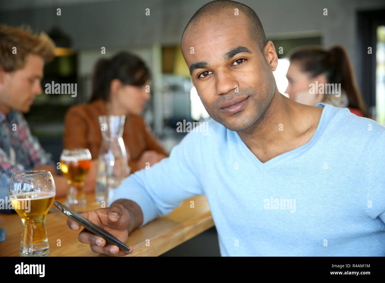 Man sitting at snack bar table checking messages Stock Photo Alamy