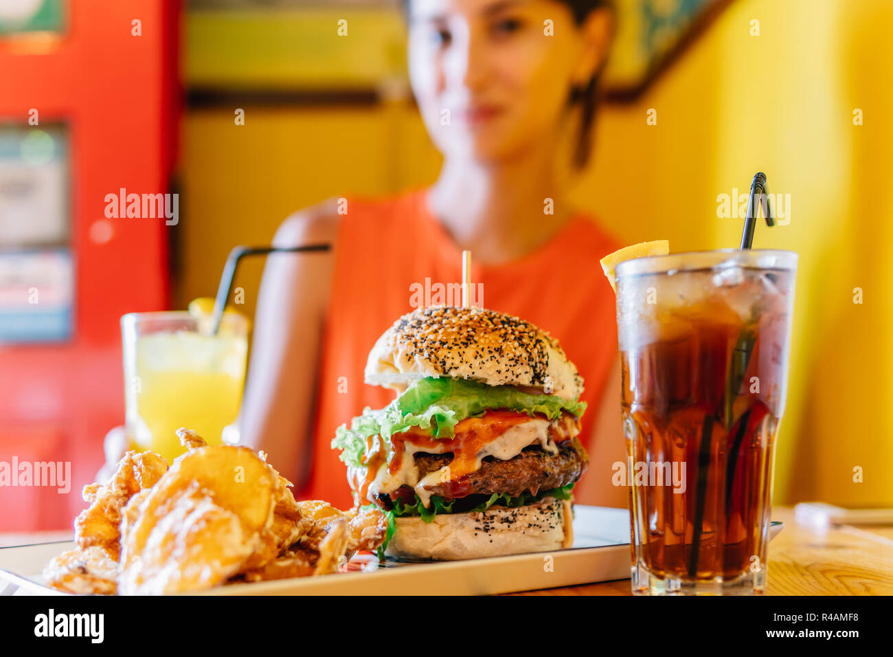 Young Woman In Restaurant Enjoying Tasty Juicy American Beef Burger