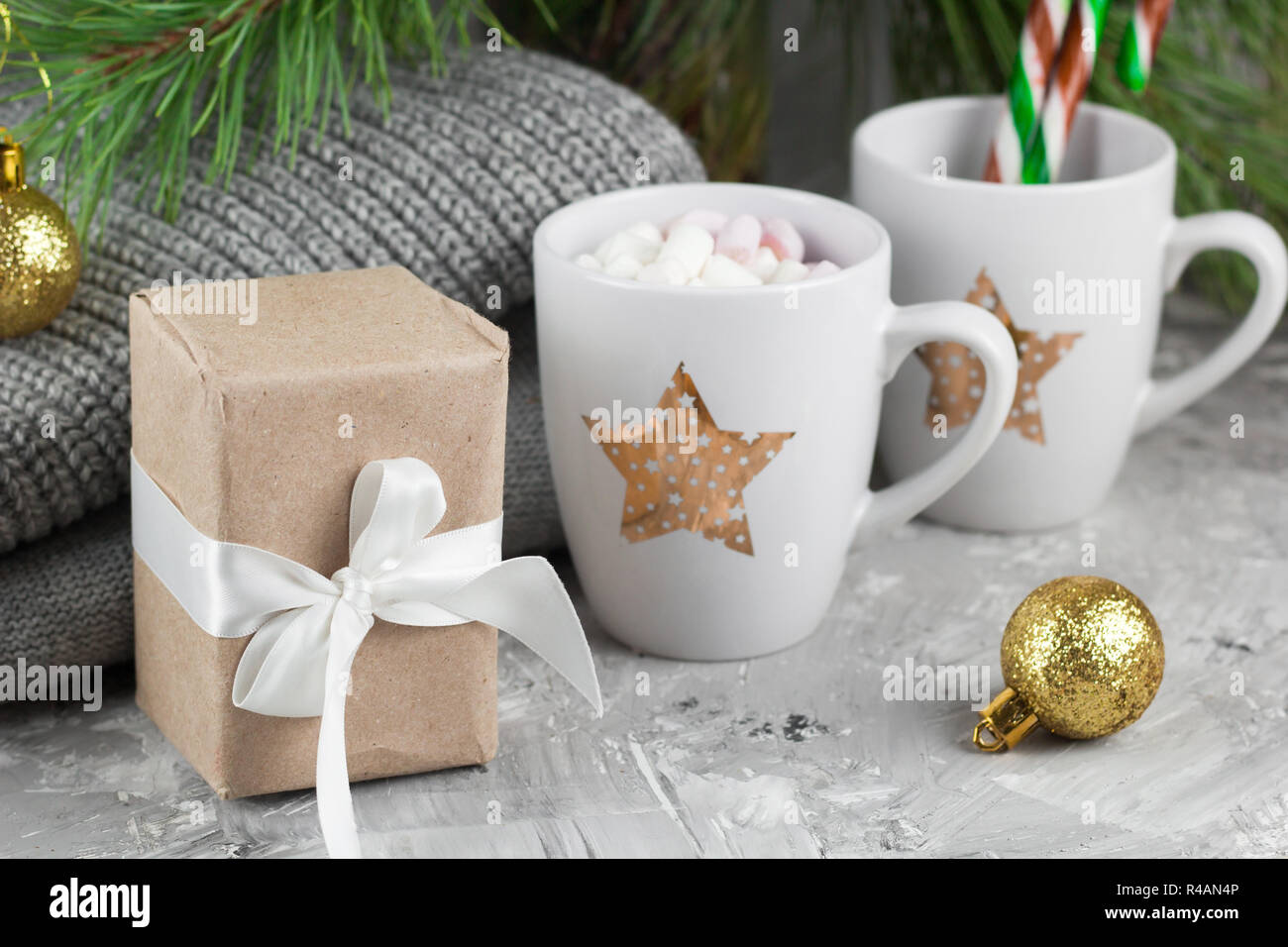 gift box and cute cups with marshmallows and candy canes under christmas tree Stock Photo