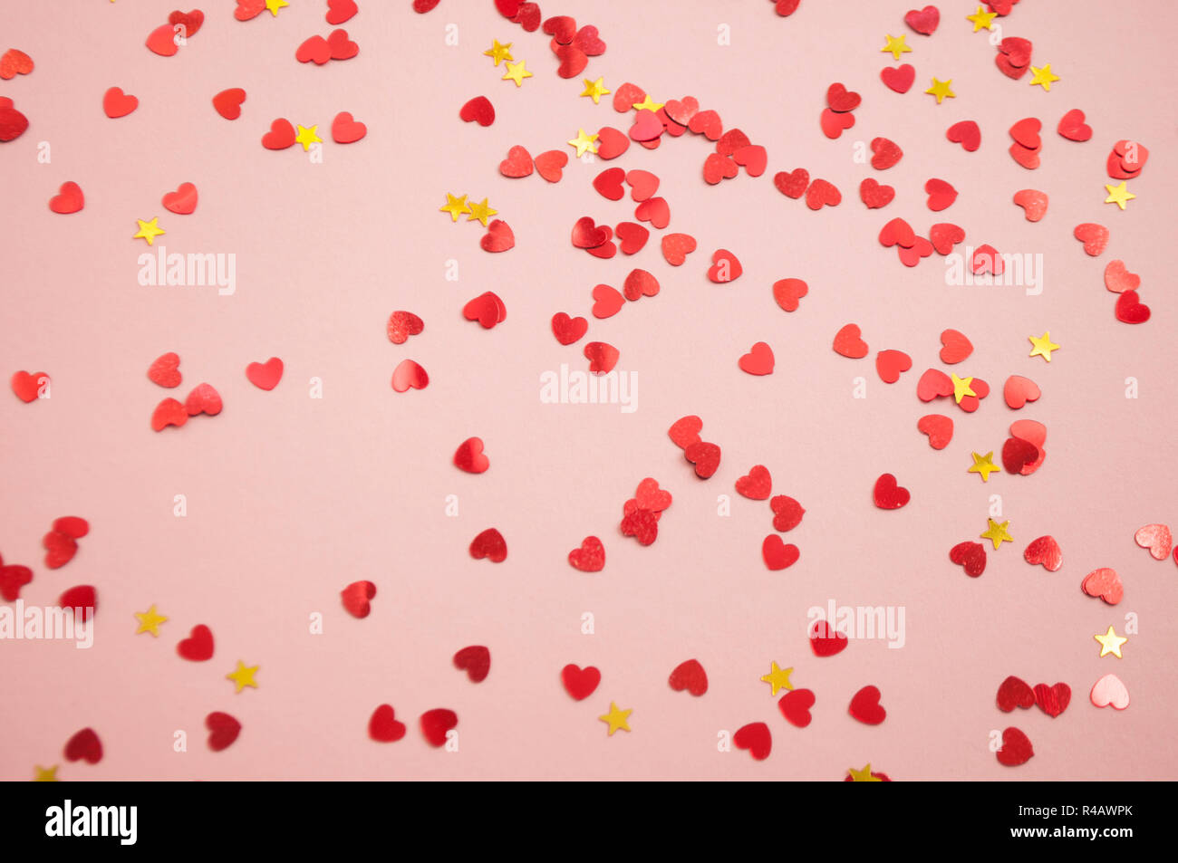 Defocused beautiful hearts and stars shaped red confetti on pink background. Stock Photo